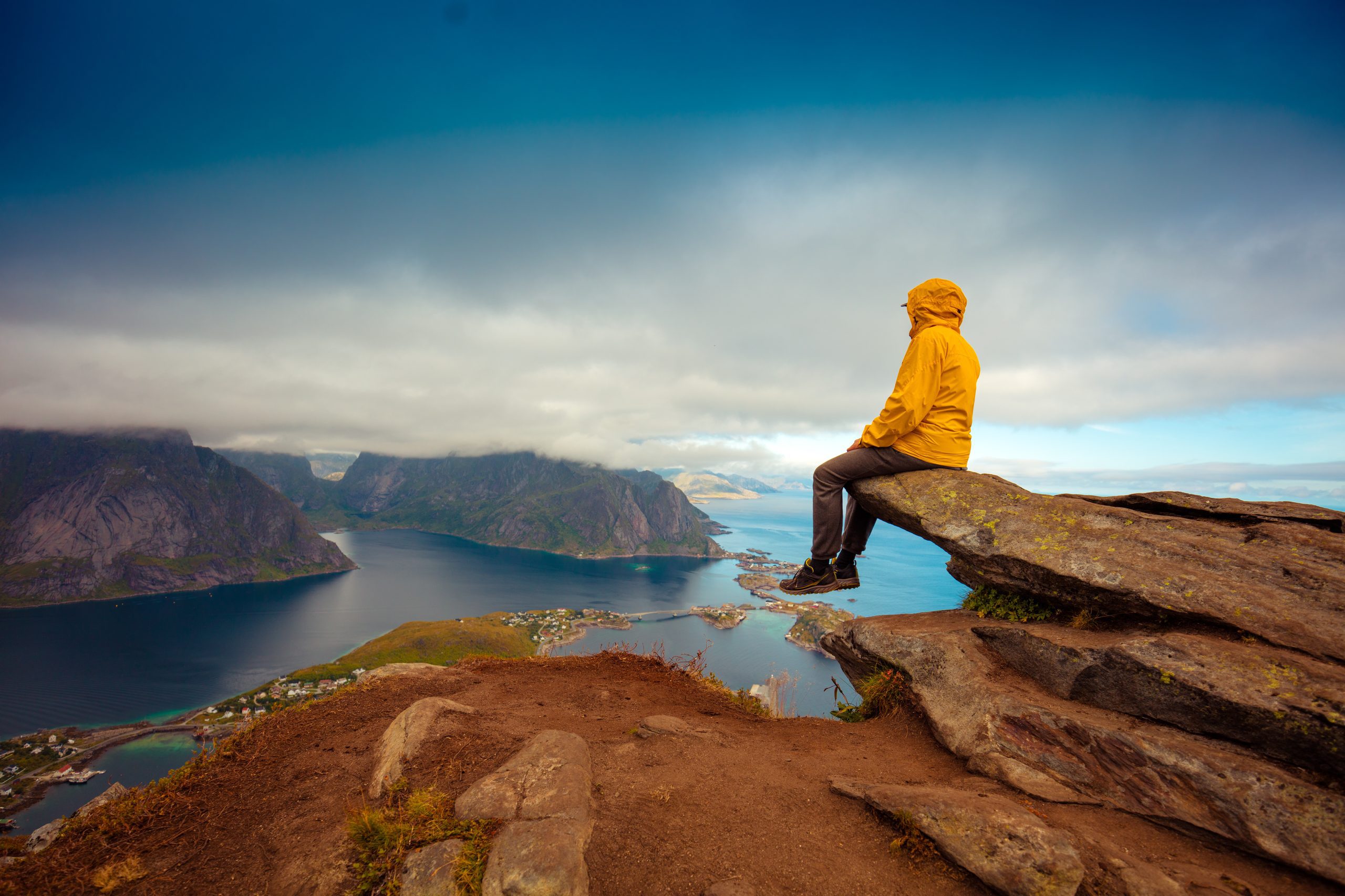 storyblocks male tourist sitting on the cliff beautiful mountain landscape of lofoten islands reine norway rLg4oK8 yM scaled