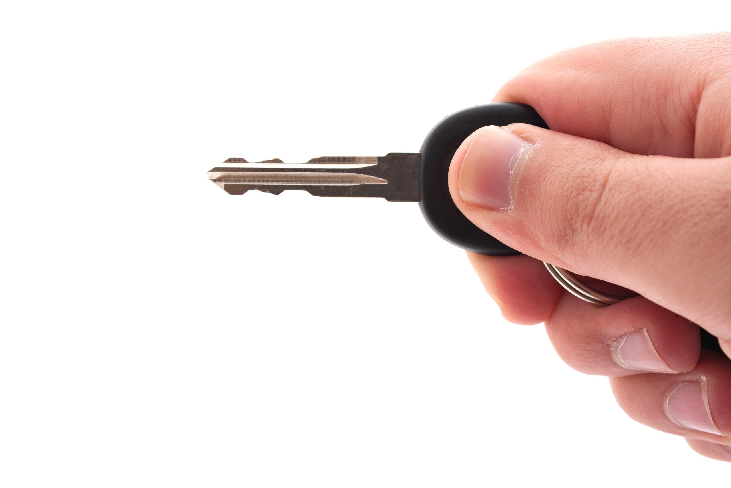a hand holding a car or house key isolated over a white background rYfeUXDRri scaled