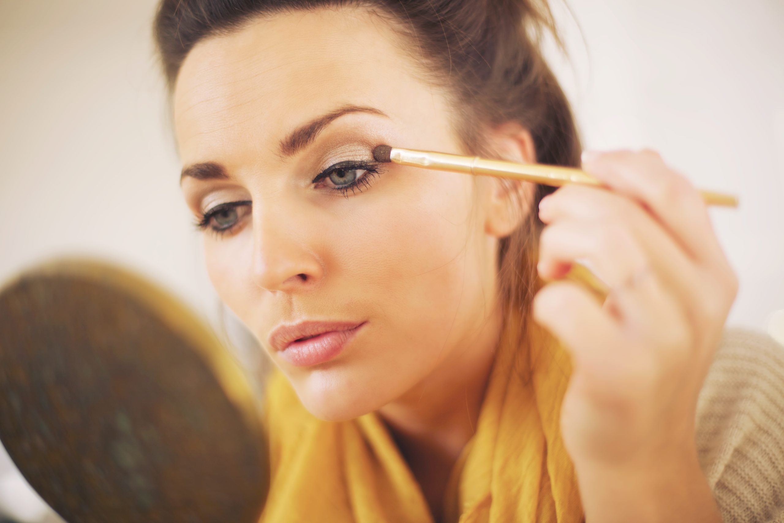 attractive woman applying makeup while looking at the mirror Hpmg1 UVYx scaled